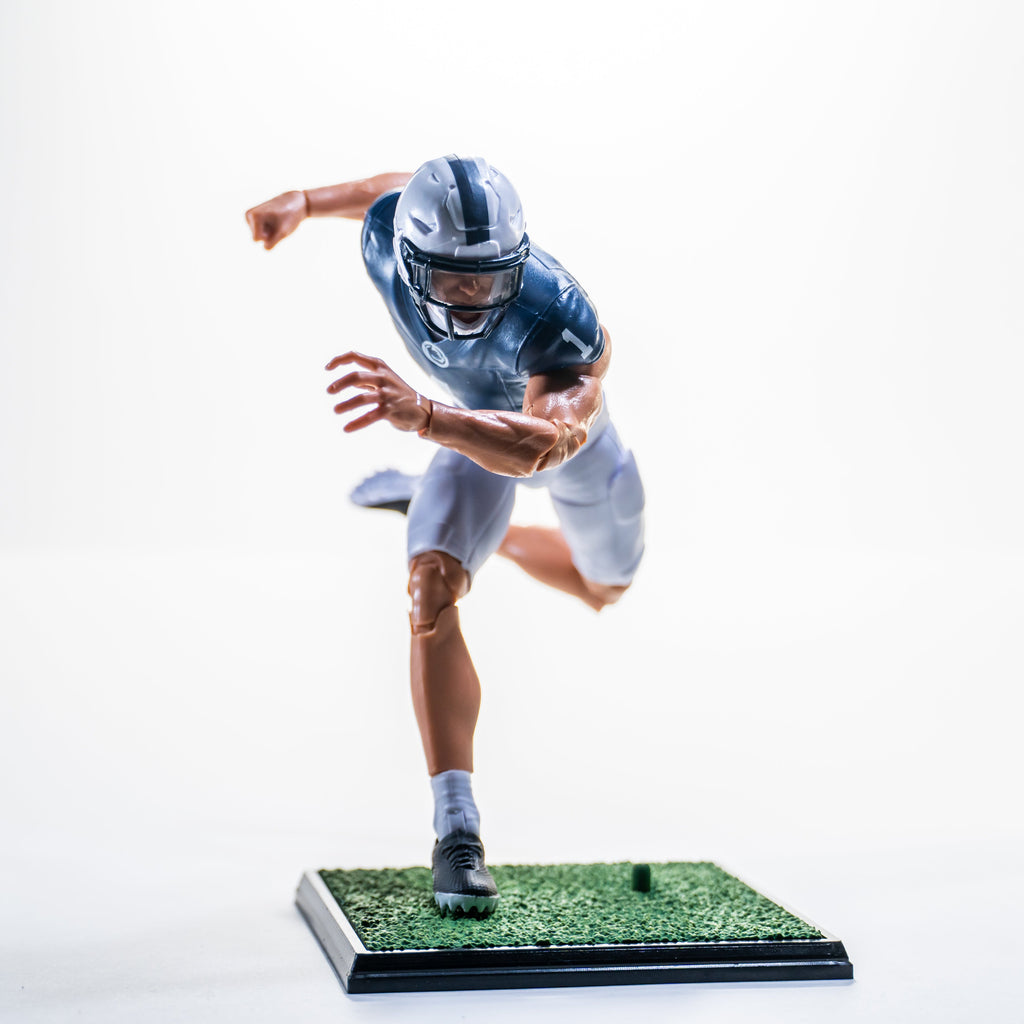 Collegiate Legends Penn State football action figure in a dynamic running pose on a green turf display stand.